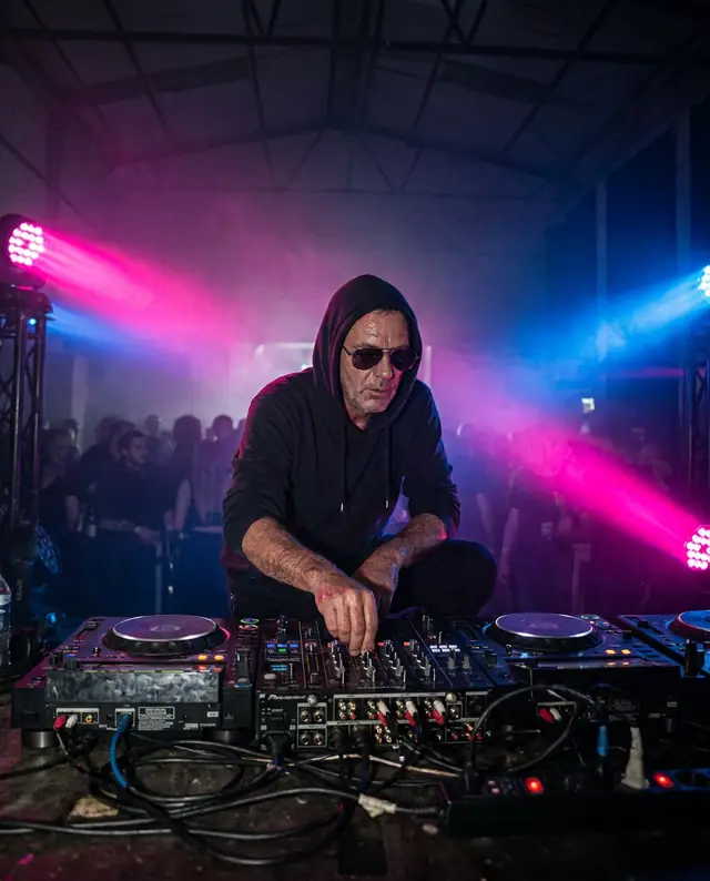 A techno DJ lit in pink and blue (illustrative image, fictional artist)